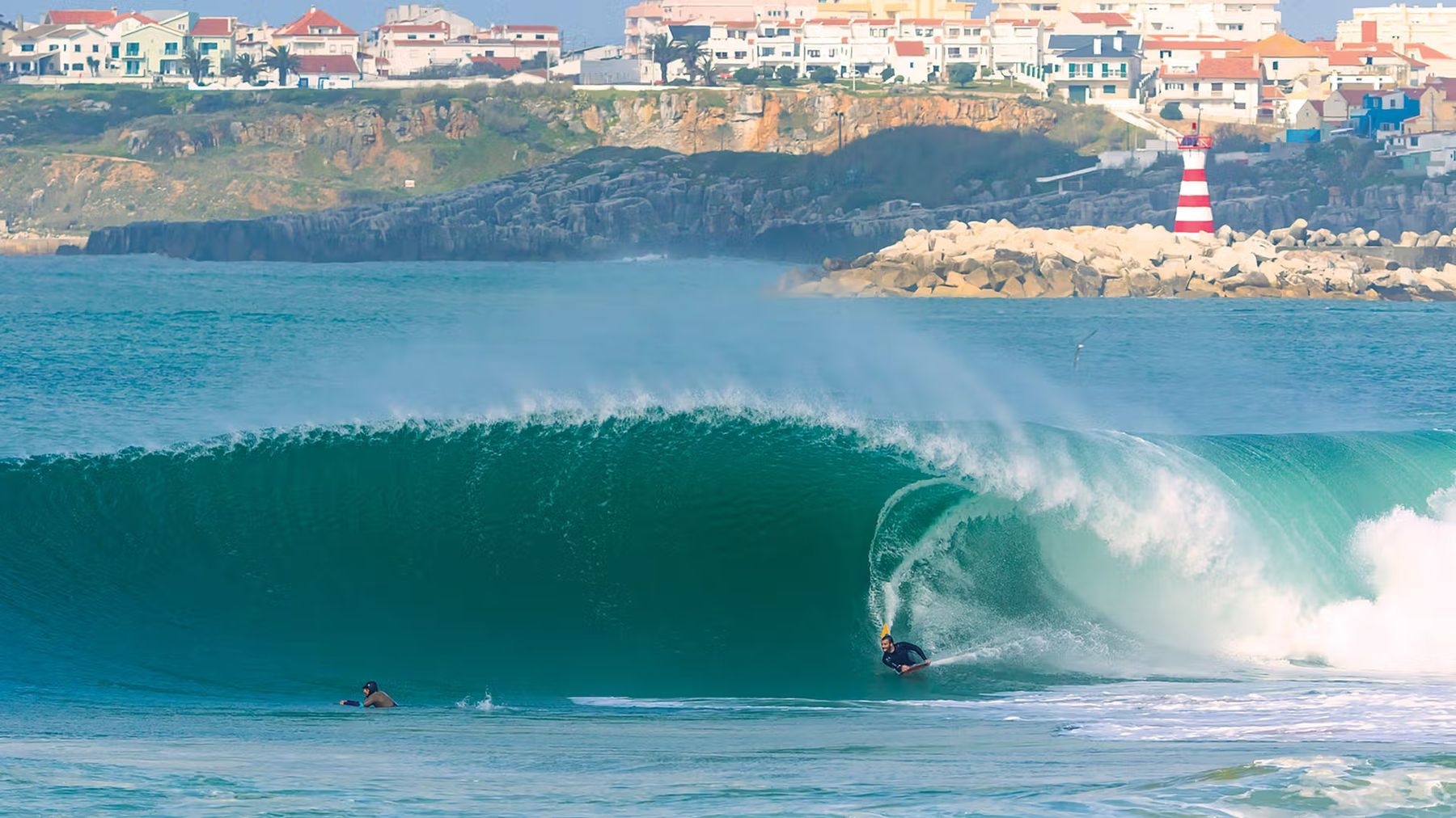A perfect barrel breaking below the cliffs and lighthouse of Peniche